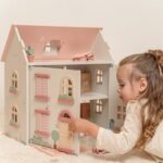 niña jugando casa de muñecos de madera