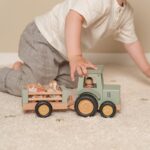 niño jugando con tractor y animales de madera